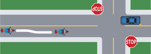 Motorcycle changing lanes as a car is turning left at an intersection.