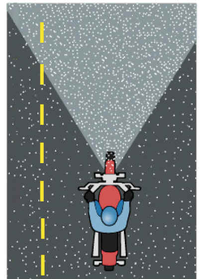 Rider driving on a road throught snowfall with low beam lights on